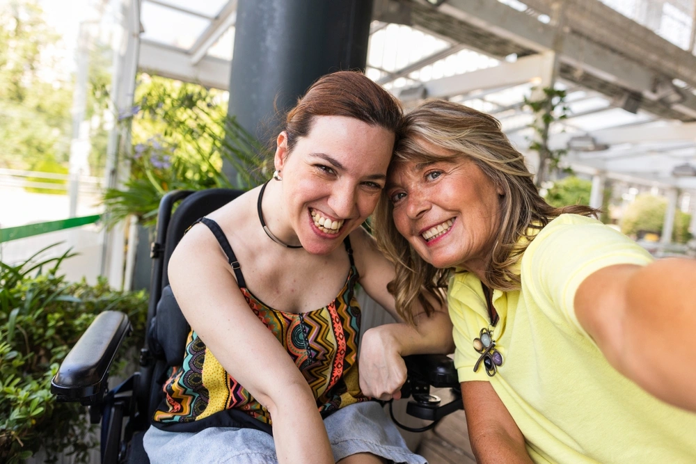 Disabled women on wheelchair smiling for a selfie with mother